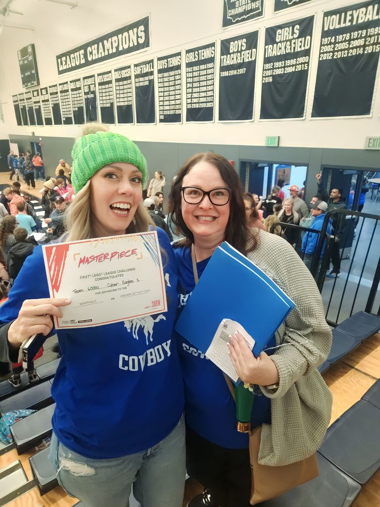 Two teachers holding up a first place certificate for the Chimacum Robotics Team, Cyber Eagles.
