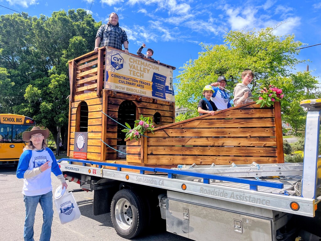 4 kids and a teacher riding on the student built wooden ship at the Rhody Parade.