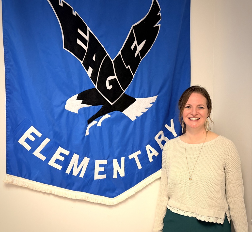 Katie Bensch standing in front of the Chimacum Elementary School Eagles Banner