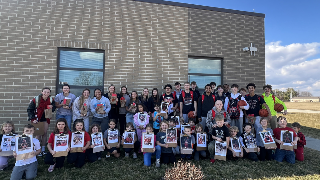 members of the varsity basketball team pose with second grade students
