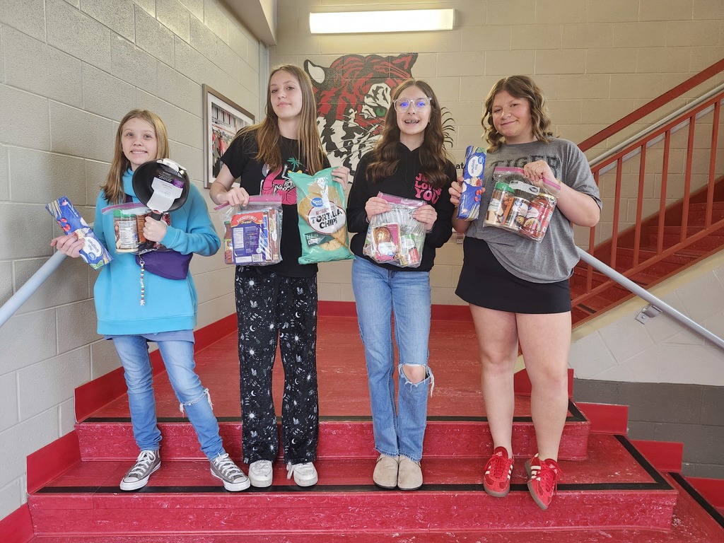 students posing with canned goods for a food drive