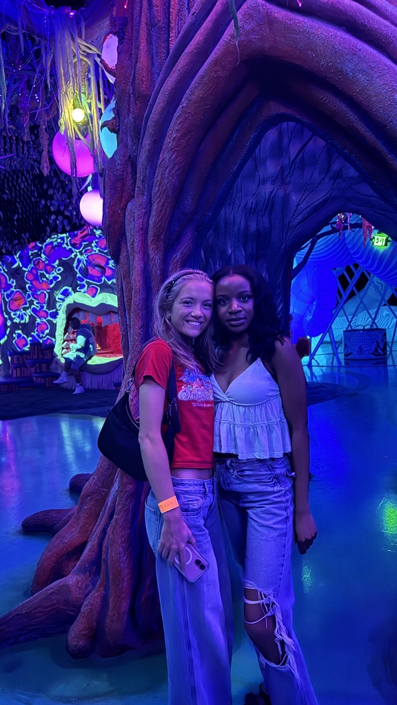 two students posing in front of an art sculpture
