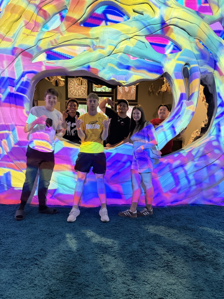 students posing in front of an art installation