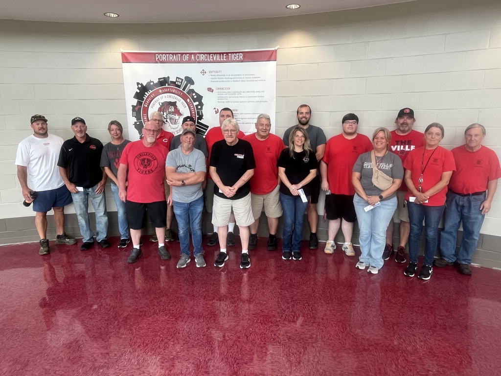 our custodial and maintenance teams post in front of the portrait of a tiger sign