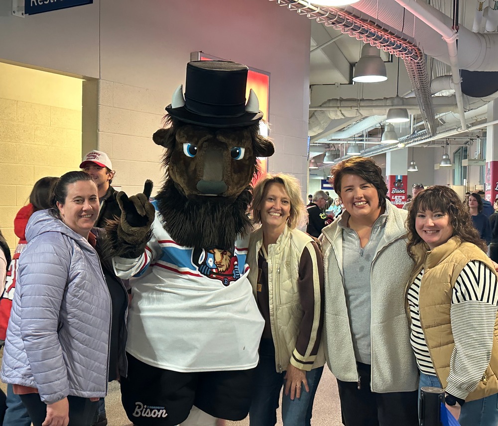 Four elementary teachers are posing with Abe, the Bloomington Bison mascot.