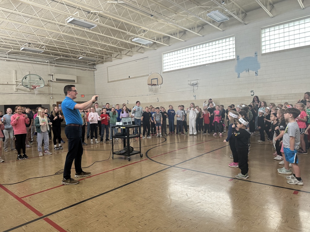 Students and staff standing learning the severe weather dance from a meteorologist