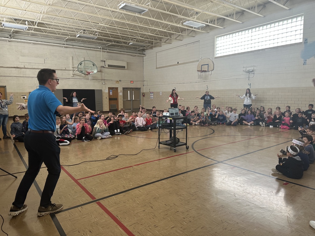 Students sitting and staff standing learning the severe weather dance from a meteorologist
