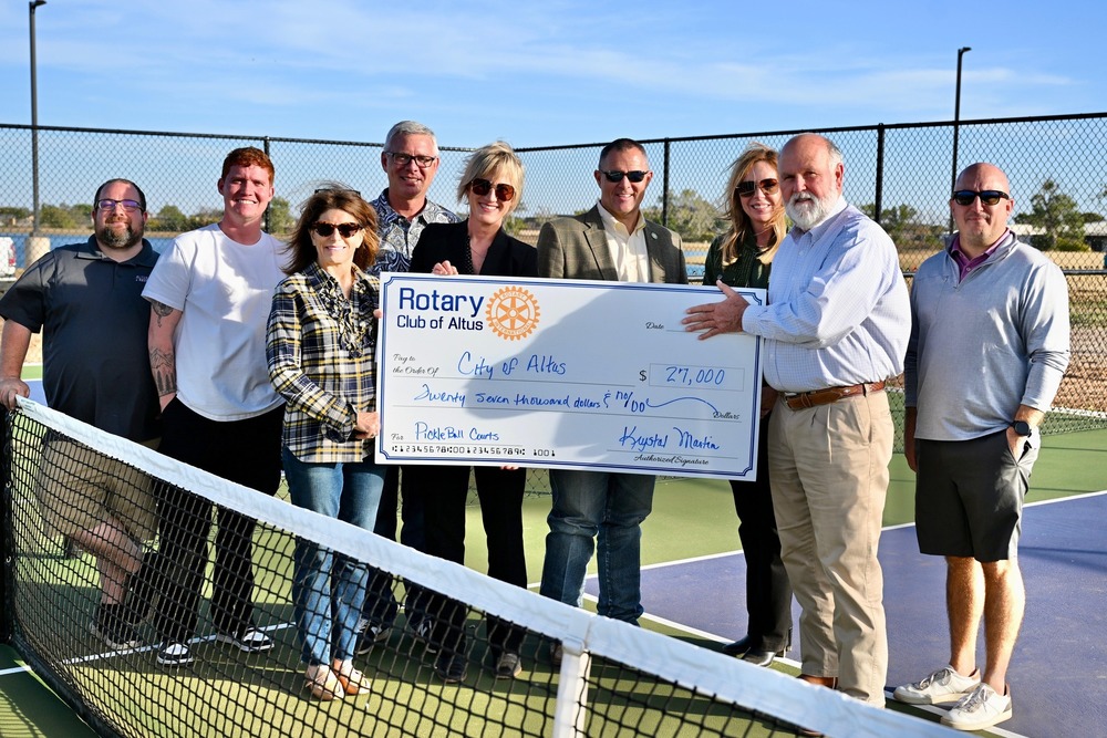 Group of Altus Rotary Club members and City of Altus staff standing together on the new pickleball courts near the reservoir, smiling and holding a large ceremonial check for $25,000 supporting the court project.