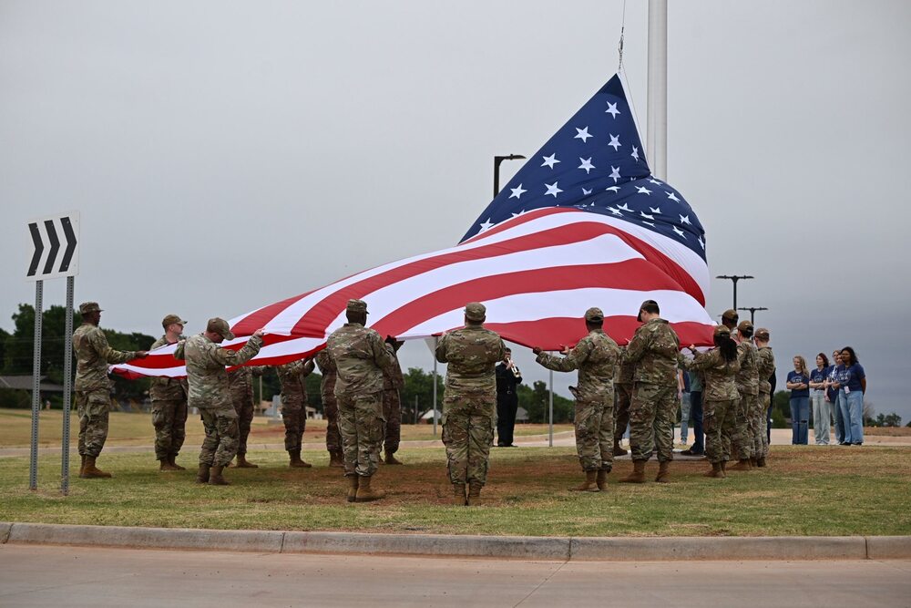Altus Air Force Base Color Guard members hold a large American flag near the base of the reservoir flagpole.