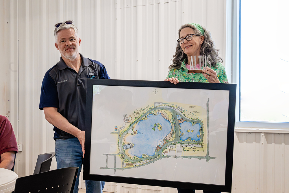 Mindy Smiley and Chris Riffle holding a framed sketch of the Altus Reservoir vision during a presentation at the Altus Community Center.