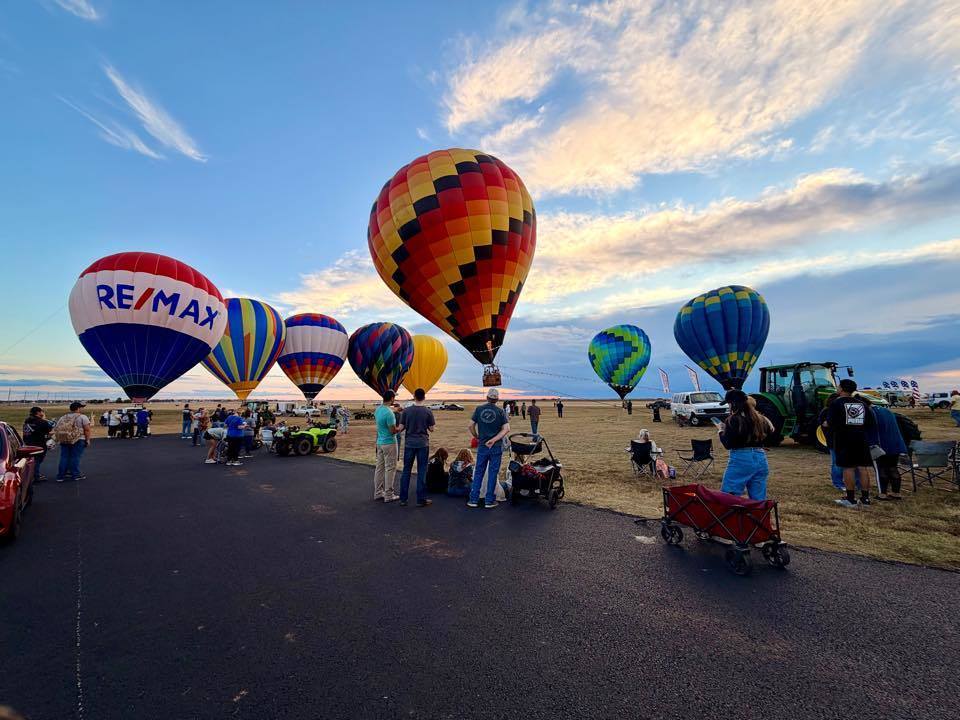 Hot Air Balloons with people standing around looking at the view. 