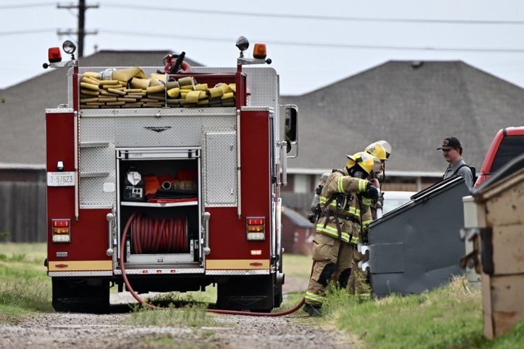 2 firefighters, putting out a fire in an alley dumpster