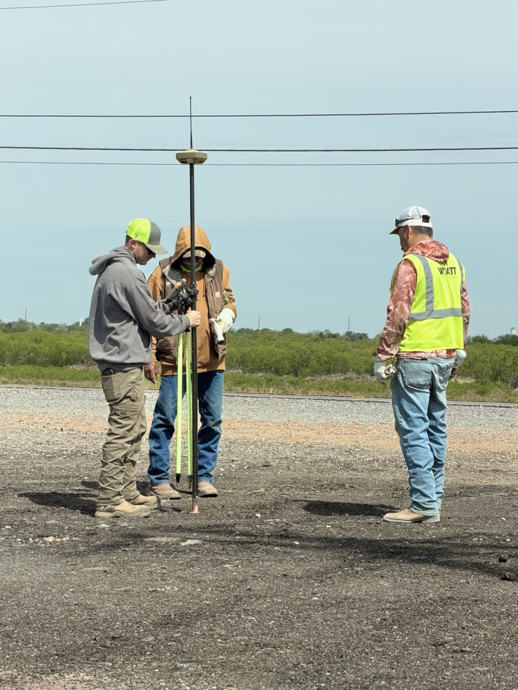 City crews conducting field measurements, excavation work with heavy equipment near utility infrastructure, and coordinated street work at an intersection in Altus.