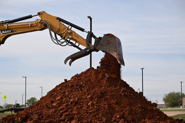 City crews conducting field measurements, excavation work with heavy equipment near utility infrastructure, and coordinated street work at an intersection in Altus.