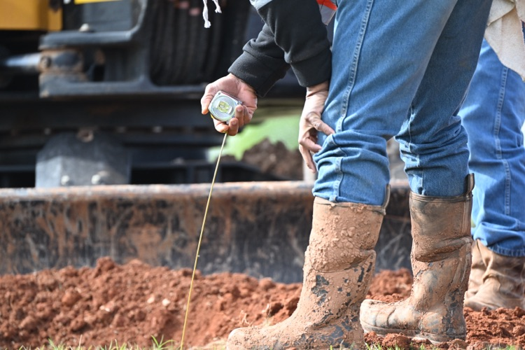 City crews conducting field measurements, excavation work with heavy equipment near utility infrastructure, and coordinated street work at an intersection in Altus.