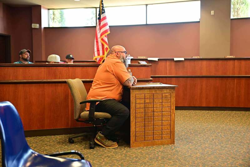 City staff member speaking at a podium in a municipal meeting room.