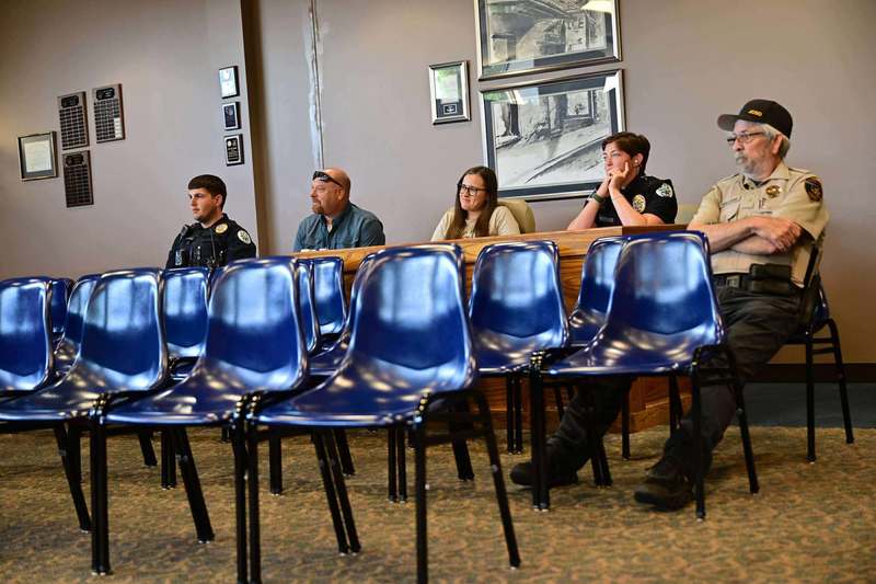 Group of police officers seated in blue chairs, listening during a training session.