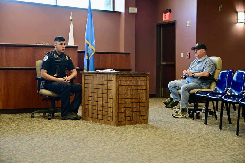 Police officer seated at a desk in a courtroom-style setting during mock trial training