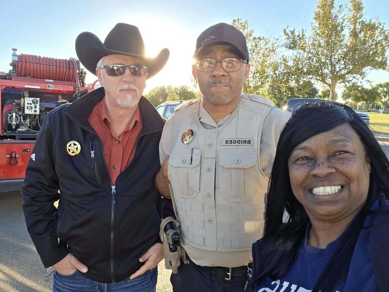 Two members of the Jackson County Sheriff’s Department stand with a smiling woman during the community birthday parade in Altus.