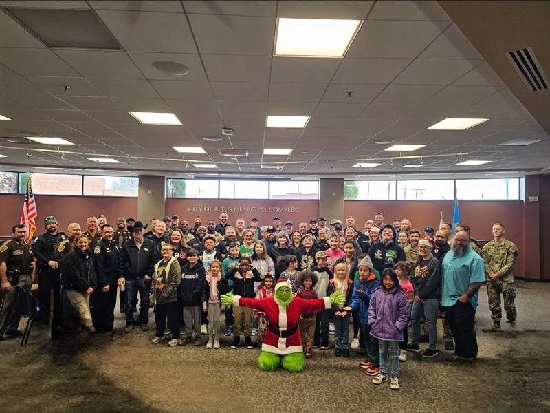 Families and children gather indoors during the Cops and Kids Christmas event, surrounded by officers and community partners.