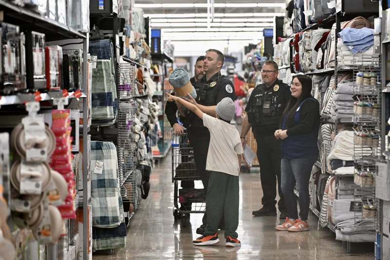 A police officer shops with a child in a store aisle during the Cops and Kids Christmas program.