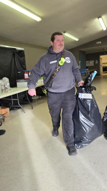 Firefighter walks inside the station carrying a large bag of donated coats.