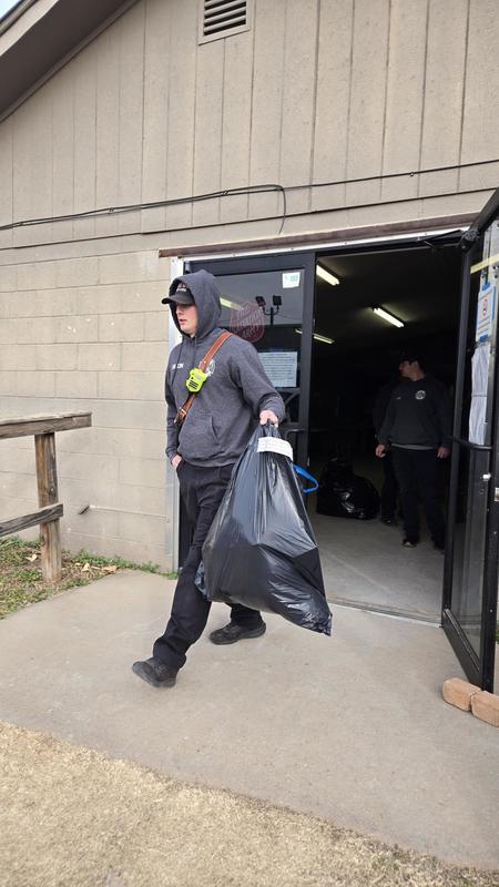 Firefighter carries a large bag of donated coats near the fire station entrance.