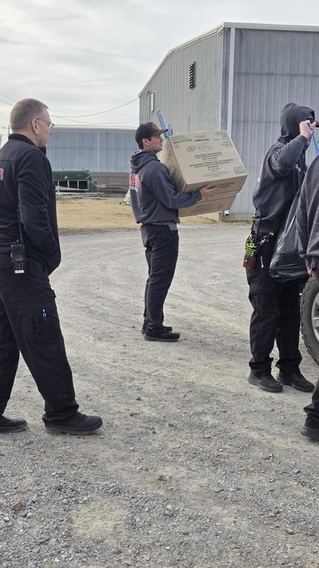 Firefighters stand outdoors on gravel during the Coats for Kids collection.