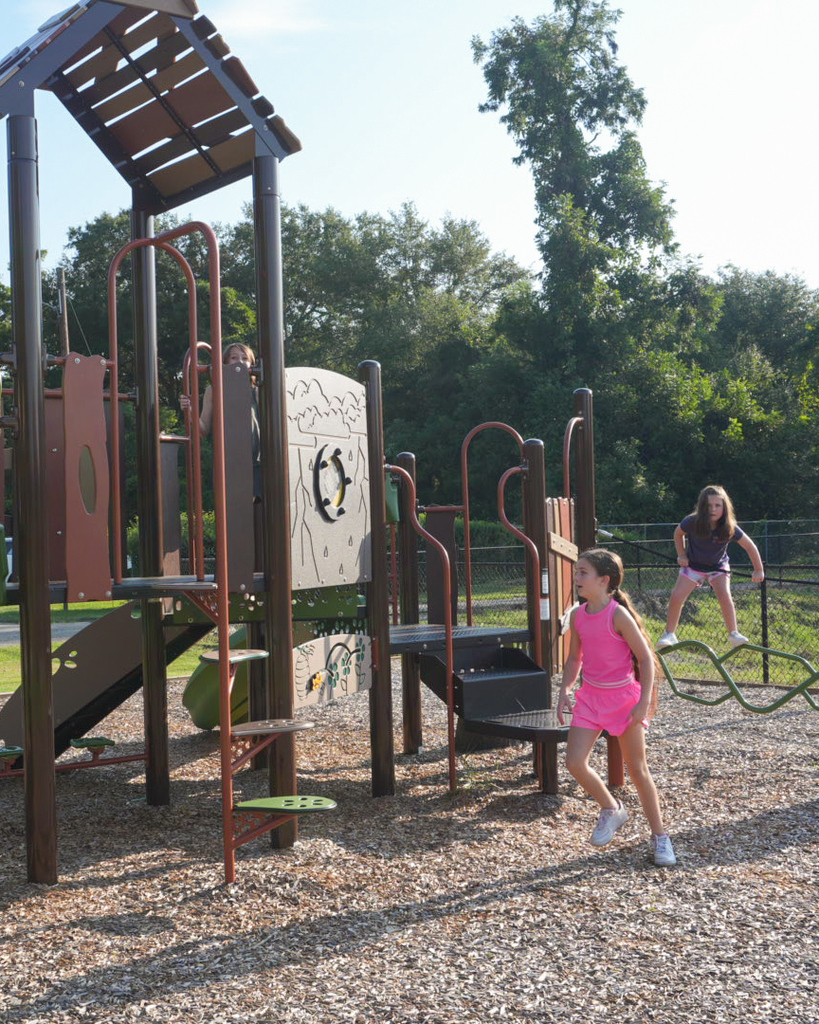 young girl in pink shirt and young girl in gray shirt playing on playground at Andrews Street Park