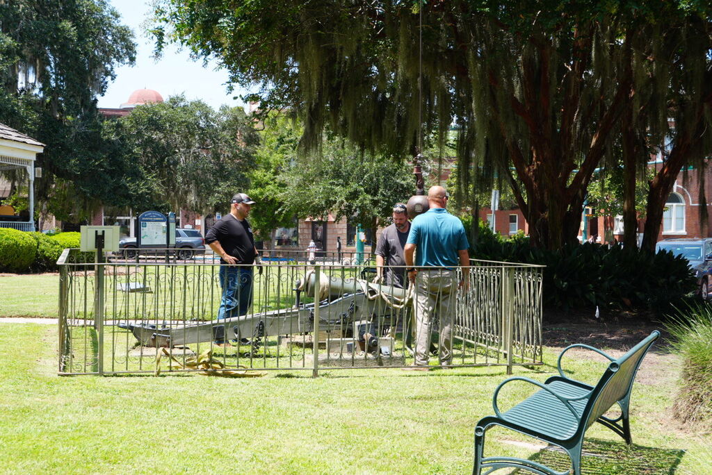 three men standing next to a civil war era cannon in willis park 