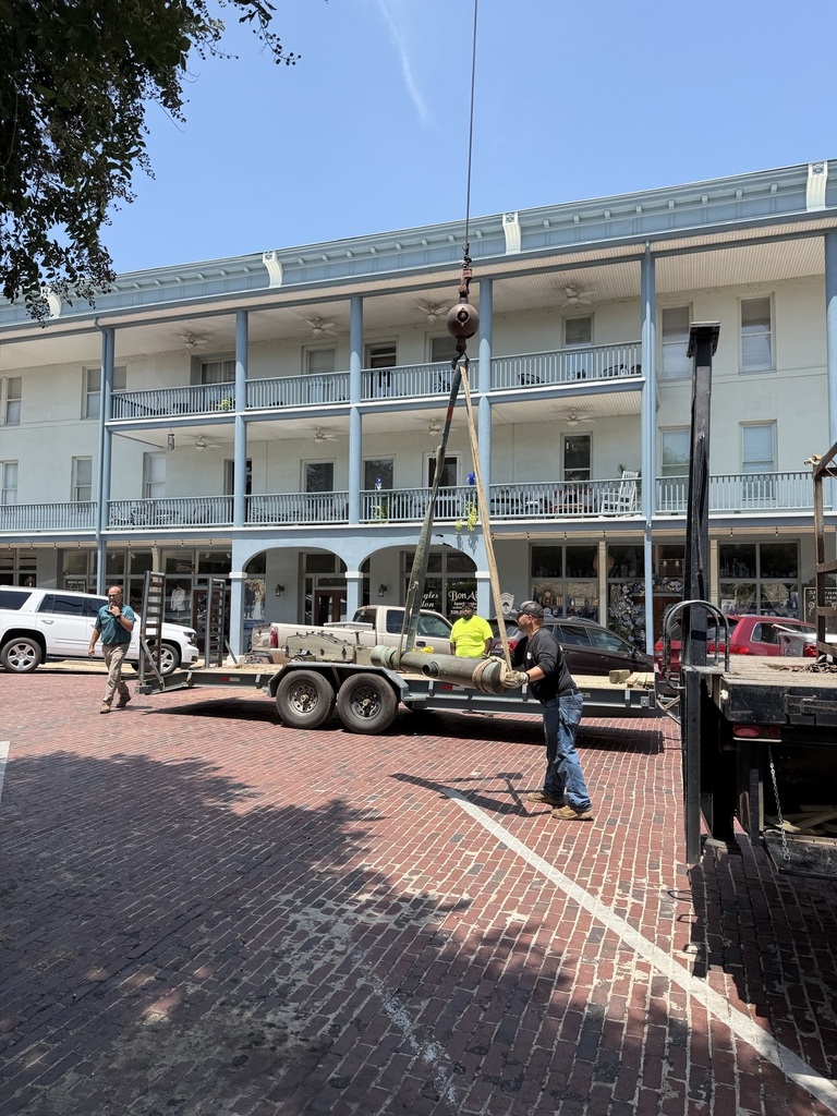 three men work to load a civil war era cannon onto a flat bed trailer