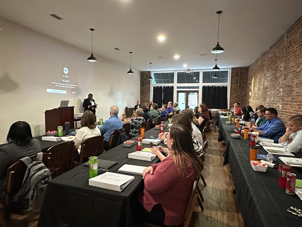 Wide view of attendees seated at tables during the Georgia Department of Community Affairs Community Planning Institute in Bainbridge. Mayor Sylvia Washington stands at the front of the room delivering welcoming remarks.