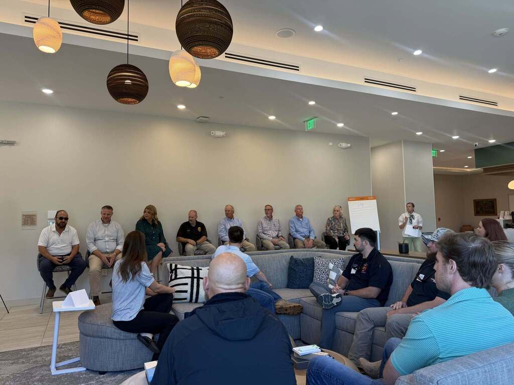 City and county government representatives participate in a panel discussion during the Leadership Decatur County session. Attendees sit on couches and chairs facing the panel in a large meeting space.