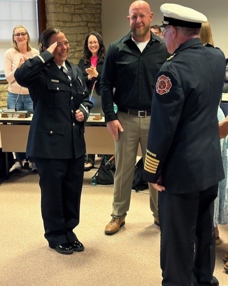 Fire Lieutenant Christina Roberts salutes Ret. Winfield Fire Chief Phil DiMenza while her family looks on.