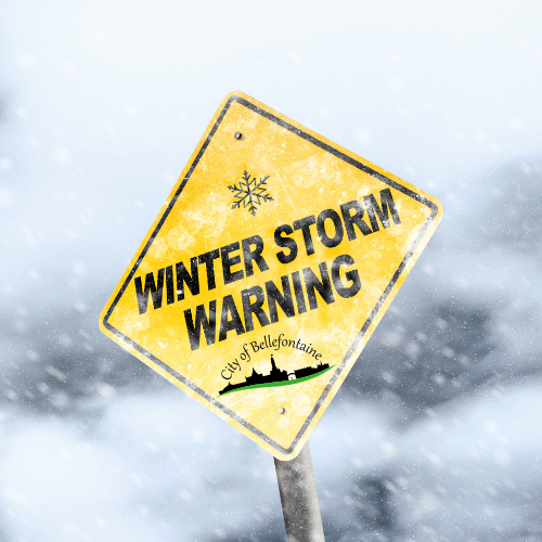 Yellow warning sign with "Winter Storm Warning" and snowflake symbol, set against a snowy, blurred background. The sign includes "City of Bellefontaine."