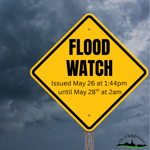 “Yellow diamond-shaped road sign reading ‘FLOOD WATCH’ with text below stating ‘Issued May 26 at 1:44pm until May 28th at 2am,’ set against a dark stormy sky background.”