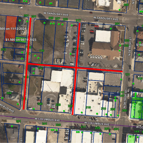 Aerial map with outlined property boundaries in blue and roads in red. Green dots indicate points of interest. Prices shown for specific areas.