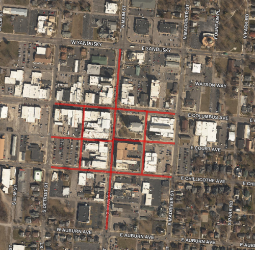 Simplified map showing a road closure for the Taste of Bellefontaine event. North Main Street and South Main Street run vertically along the left side of the map, intersecting with East Columbus Avenue, which runs horizontally across the center. A red-highlighted section of East Columbus Avenue between Main Street and Opera Street is marked as closed, with red “Road Closed” signs at both ends of the affected block. A large gray building labeled “Logan County Courthouse” appears southwest of the intersection, and the text “Oldest Concrete Street in America” is shown nearby. On the right side of the map, a gray parking area marked with a large white “P” is located along East Columbus Avenue. The map uses gray and red colors to emphasize the closure area.