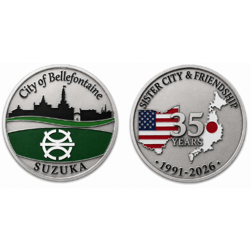 Two silver commemorative challenge coins displayed side by side on a light gray background. The left coin features the text “City of Bellefontaine” at the top and “SUZUKA” at the bottom. A black city skyline silhouette appears above a green field with a white emblem in the center. The right coin reads “SISTER CITY & FRIENDSHIP” across the top and displays “35 YEARS” over a design combining the United States and Japan, with U.S. flag elements and a red circle representing the Japanese flag. The dates “1991–2026” appear along the bottom edge, marking the 35th anniversary of the sister city relationship.