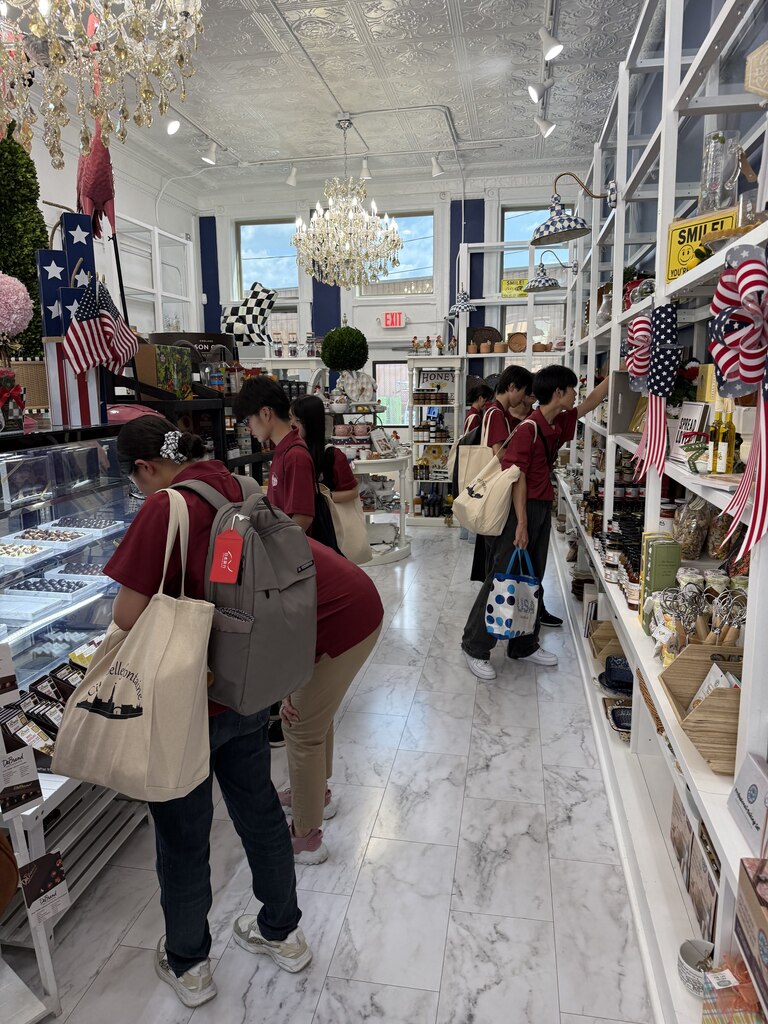 A group of people are in a store with shelves filled with items, some carrying bags.