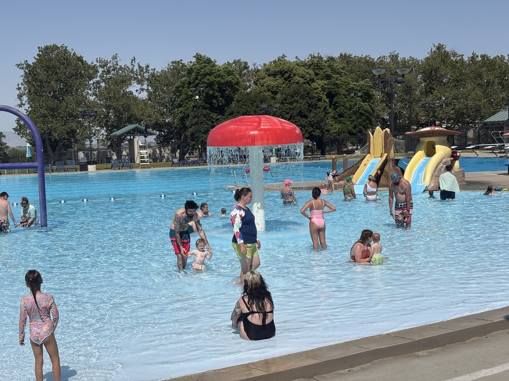An image of children and their parents playing in the shallow end of a swimming pool.