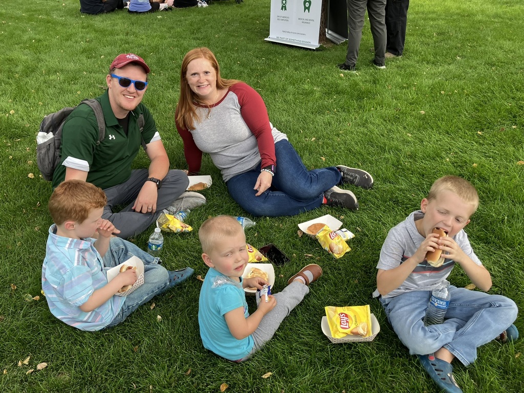 a family eats their dinner on the lawn at the community barbecue