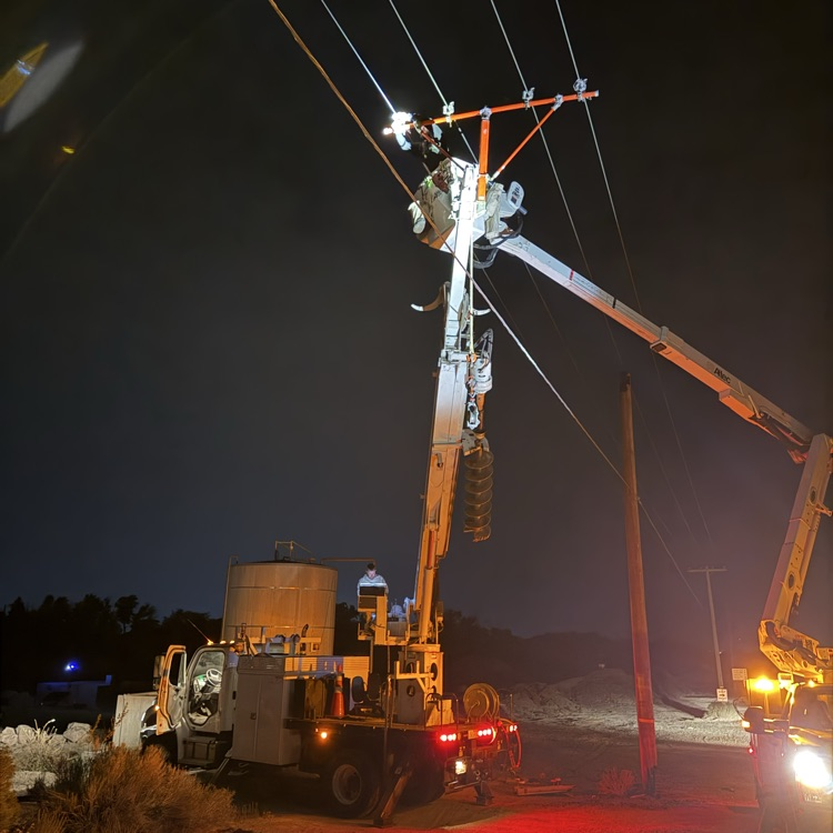 crews work on a power pole in the dark