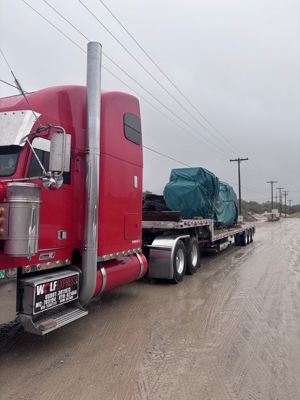 a tarp-covered generator on the back of a semi truck