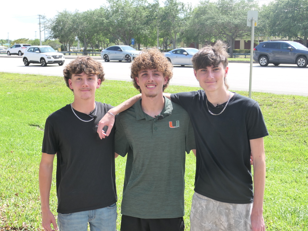 Three teenaged boys standing arm in arm with a roadway in the background