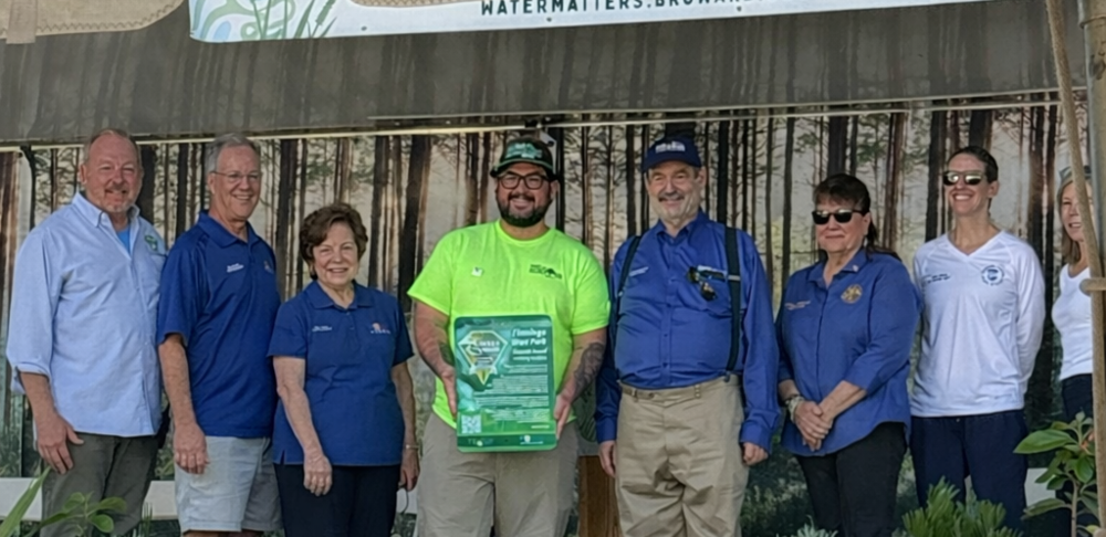 Several people on a stage and a City employee holding a plaque