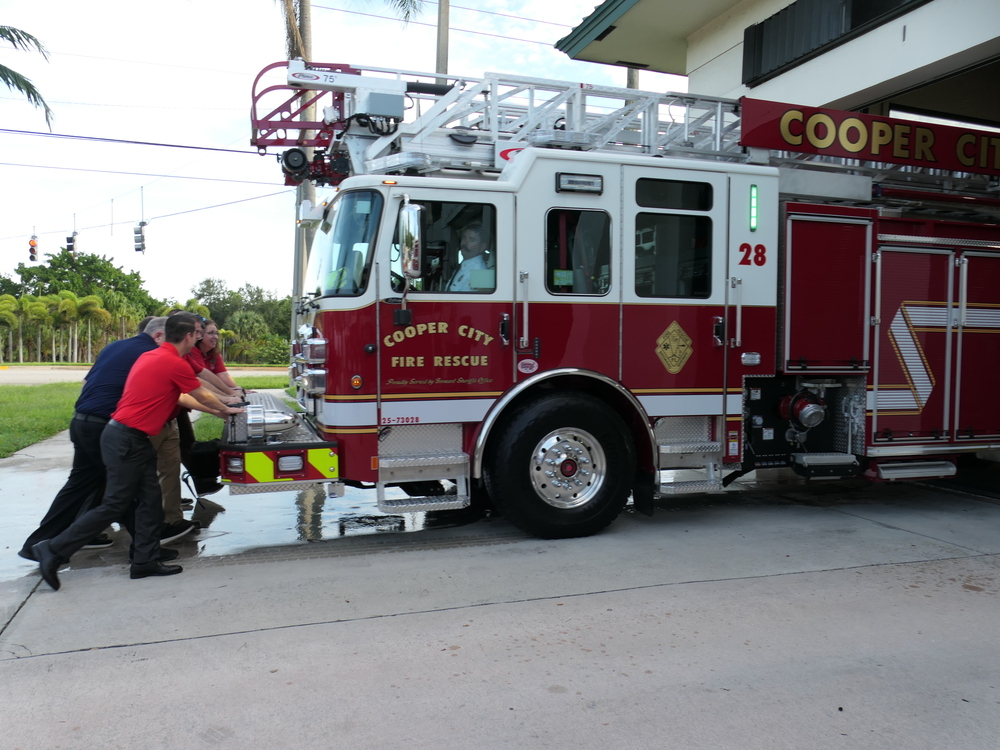 City Commissioner pushing a fire truck into a fire station in a celebratory push-in ceremony.