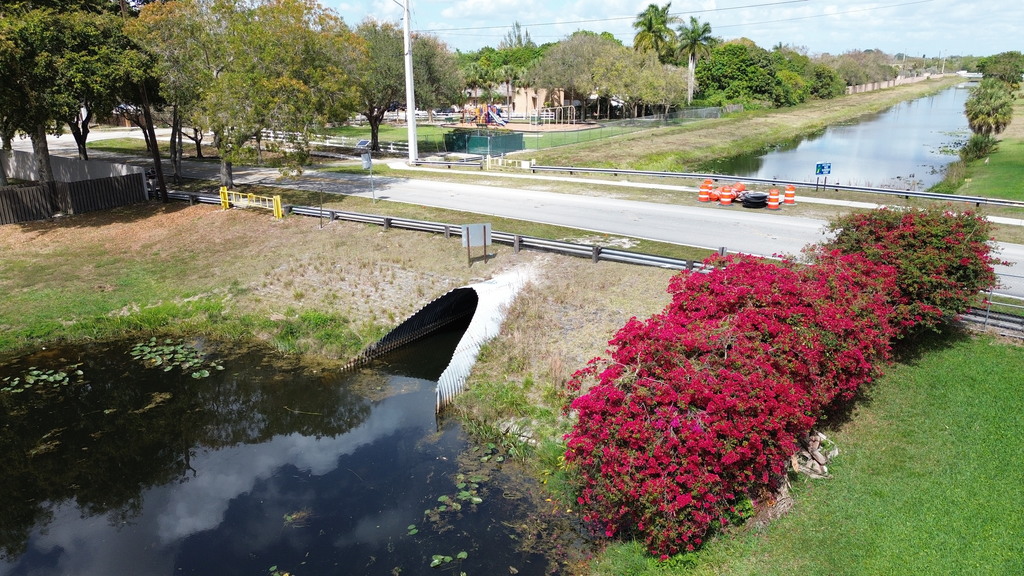 Roadway over a canal with metal culvert underneath.