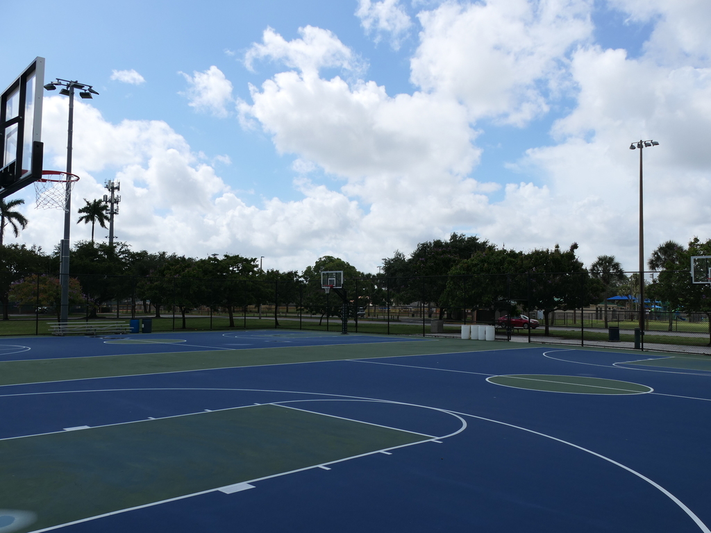 Blue and green basketball court with hoops in the foreground and background.