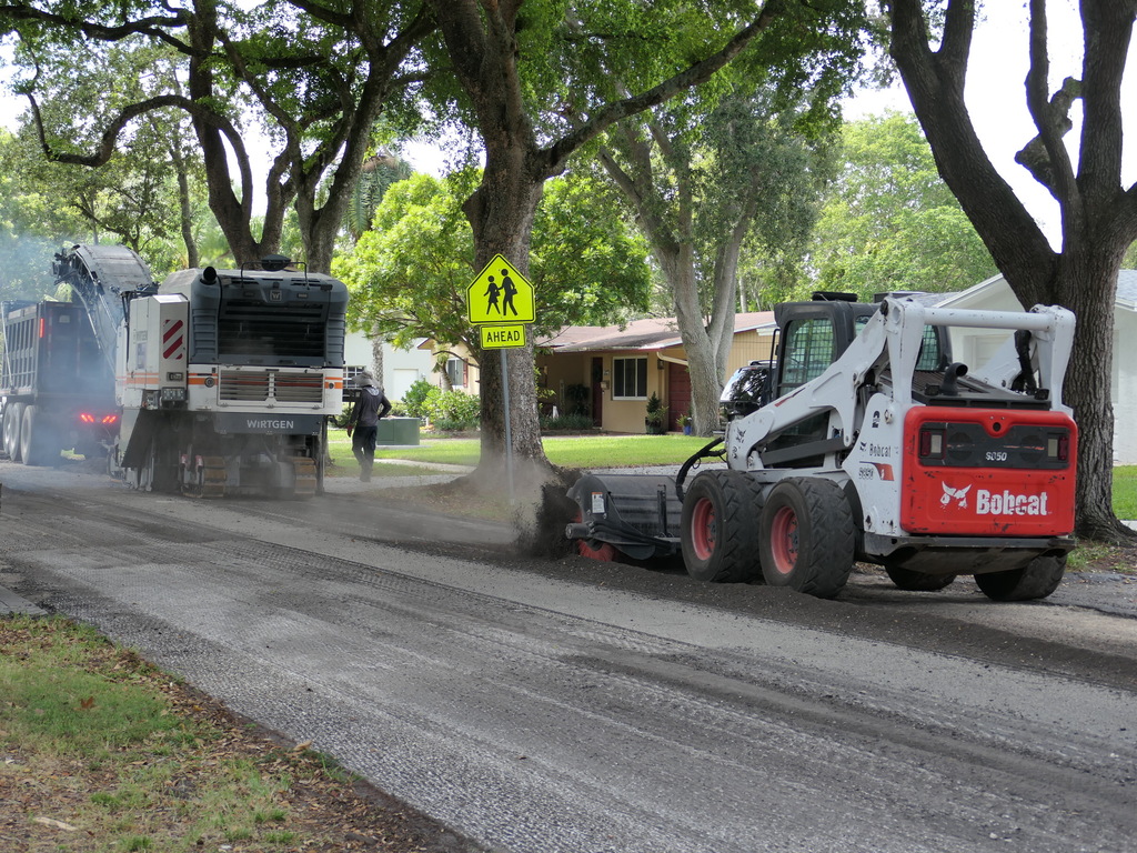Photo of heavy equipment and crew milling a roadway along a residential area.
